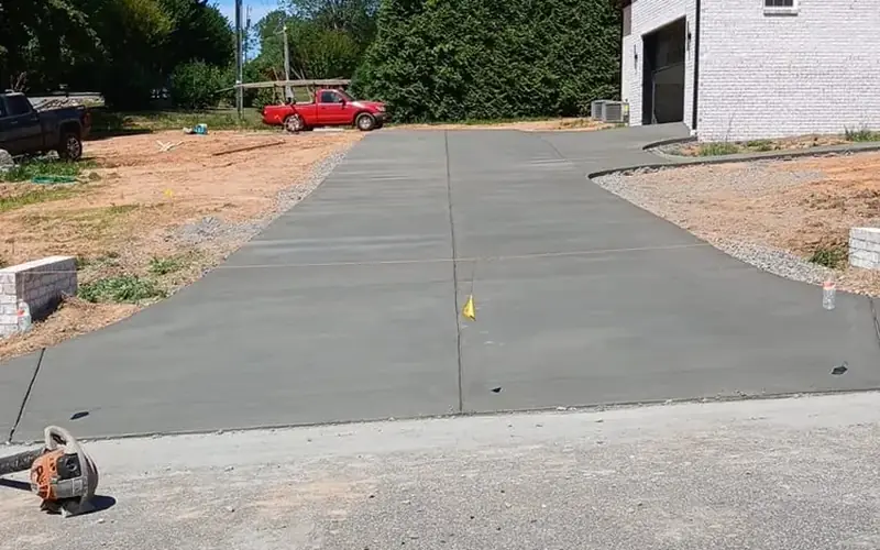 New concrete driveway beside a brick home