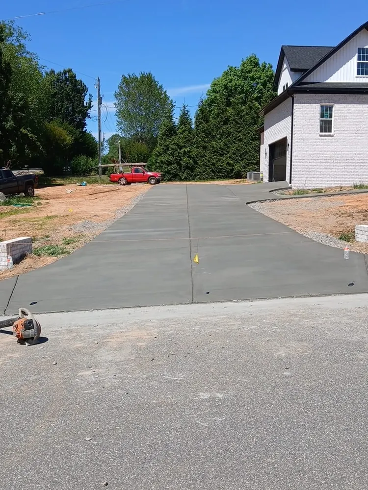 New broom-finish concrete driveway beside a brick home in Yadkin County NC